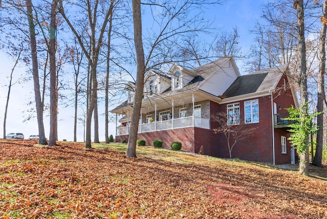 view of side of property featuring brick siding and covered porch