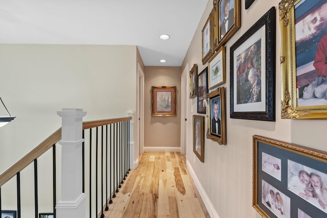 hallway with recessed lighting, an upstairs landing, baseboards, and light wood finished floors