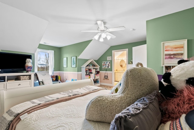 bedroom featuring a wainscoted wall, lofted ceiling, ceiling fan, and ensuite bathroom