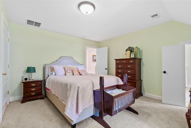 bedroom with visible vents, light colored carpet, and vaulted ceiling