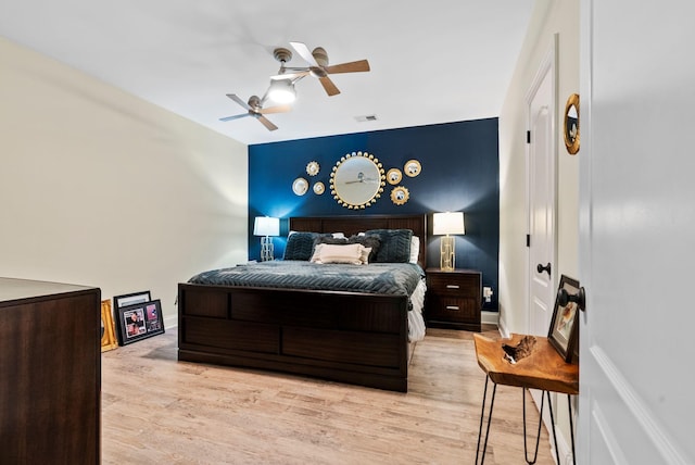 bedroom featuring light wood-type flooring, baseboards, visible vents, and ceiling fan