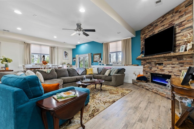 living area with visible vents, a stone fireplace, recessed lighting, wood finished floors, and a ceiling fan