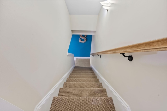 stairway featuring baseboards and carpet floors