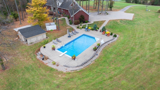 outdoor pool with an outdoor structure, a patio area, a diving board, and a lawn