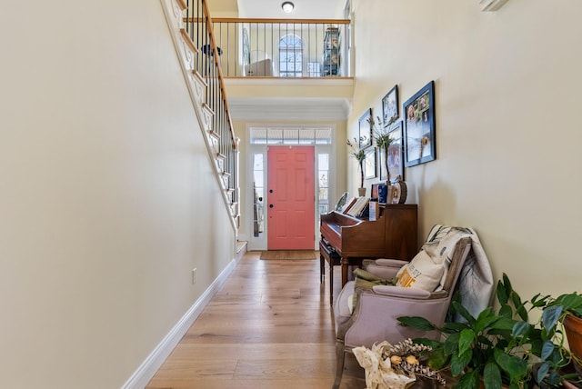 entrance foyer with light wood-style floors, baseboards, and a towering ceiling