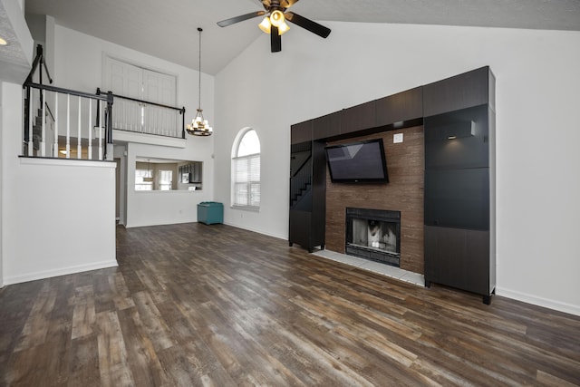 unfurnished living room featuring ceiling fan with notable chandelier, dark hardwood / wood-style flooring, a textured ceiling, and high vaulted ceiling