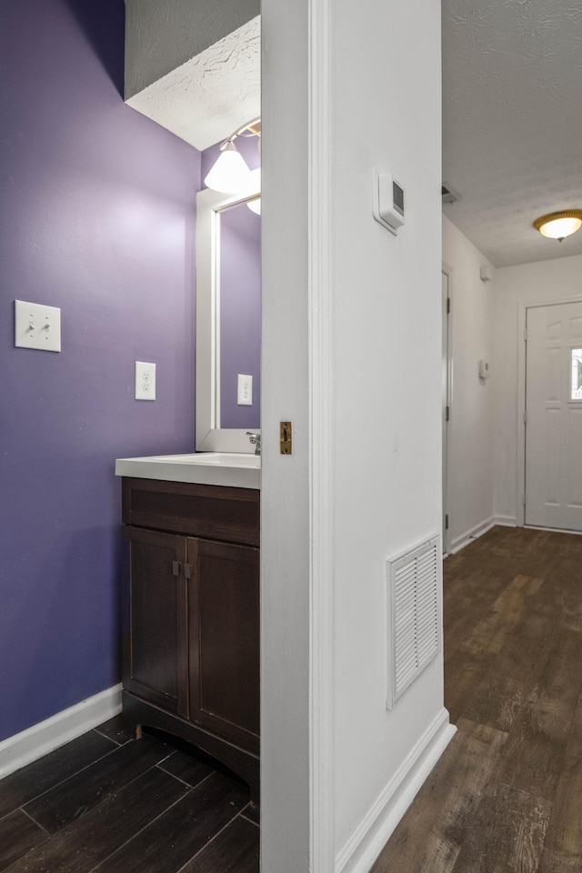 bathroom with a textured ceiling, vanity, and hardwood / wood-style flooring