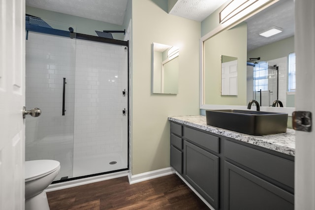 bathroom with a textured ceiling, toilet, a shower with door, vanity, and hardwood / wood-style flooring