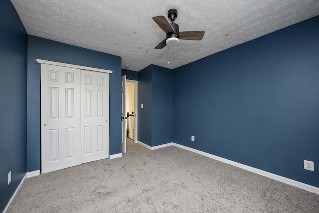 unfurnished bedroom featuring ceiling fan, a closet, light carpet, and a textured ceiling