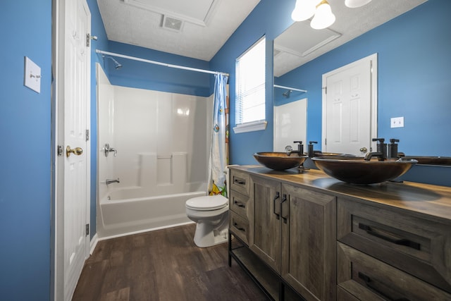 full bathroom featuring hardwood / wood-style floors, shower / bath combo, vanity, toilet, and a textured ceiling