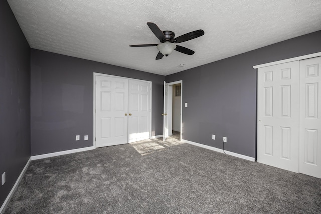 unfurnished bedroom featuring a textured ceiling, dark carpet, and ceiling fan