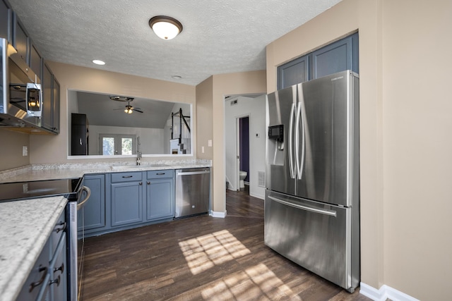 kitchen with sink, ceiling fan, a textured ceiling, appliances with stainless steel finishes, and dark hardwood / wood-style flooring