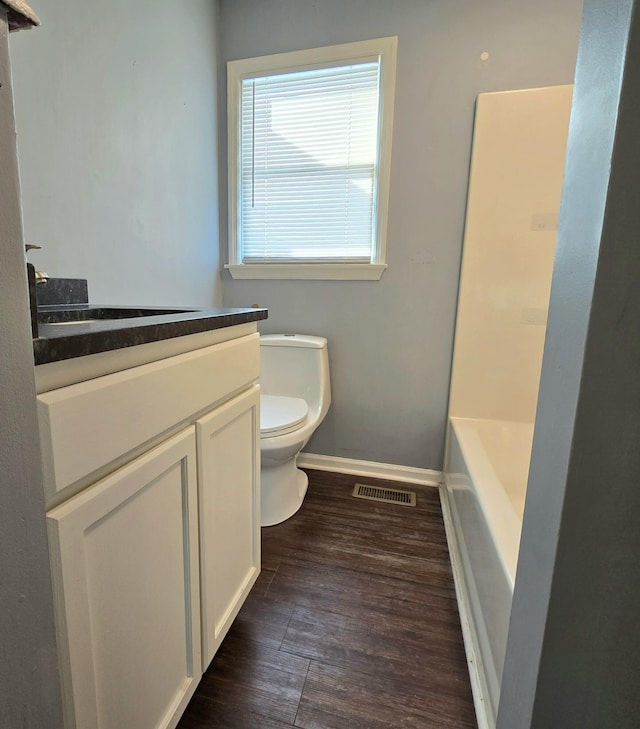 bathroom with vanity, toilet, a bathing tub, and wood-type flooring