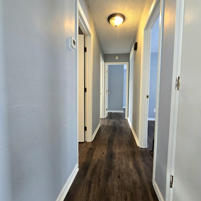 corridor featuring dark wood-type flooring and a textured ceiling