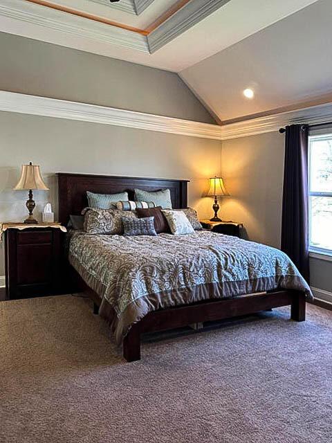 bedroom with carpet flooring, vaulted ceiling, and ornamental molding