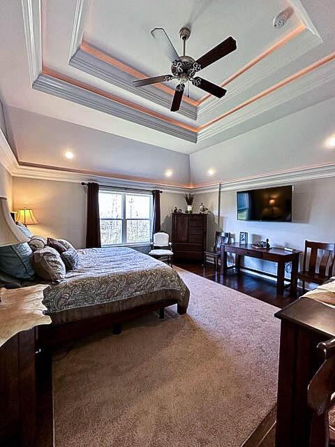 bedroom featuring ceiling fan, dark hardwood / wood-style flooring, crown molding, and a tray ceiling