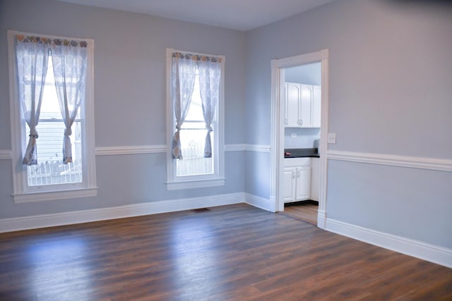 spare room with dark hardwood / wood-style flooring and plenty of natural light