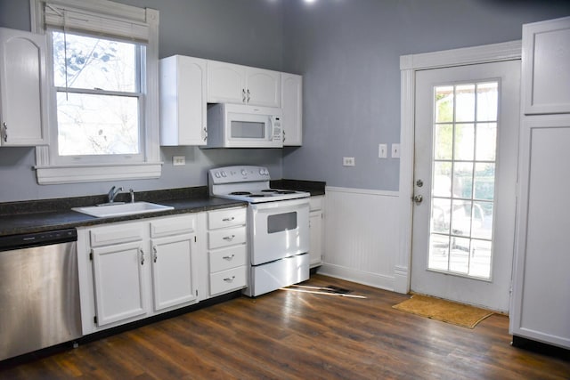 kitchen with white cabinets, dark hardwood / wood-style floors, white appliances, and sink