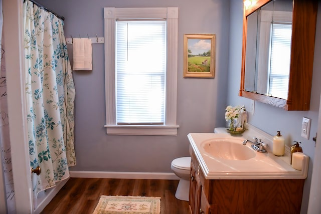 bathroom with plenty of natural light, vanity, wood-type flooring, and toilet