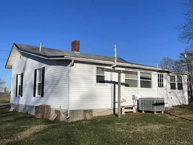 rear view of house with central AC and a yard