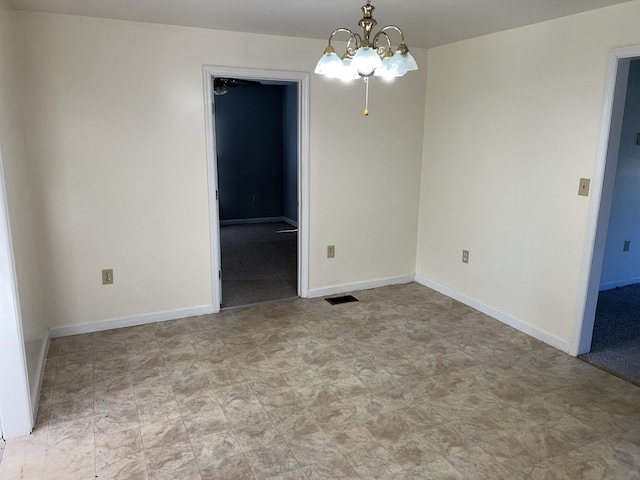 unfurnished room featuring a chandelier