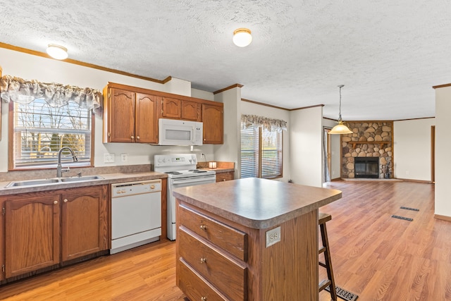 kitchen featuring pendant lighting, sink, white appliances, a center island, and a fireplace