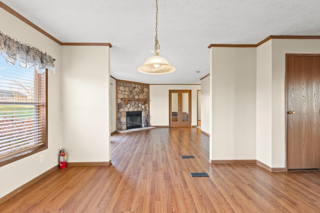 unfurnished living room featuring ornamental molding, a fireplace, light hardwood / wood-style flooring, and a textured ceiling