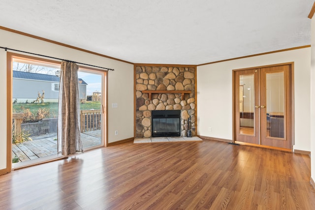 unfurnished living room featuring hardwood / wood-style flooring, a fireplace, ornamental molding, and french doors