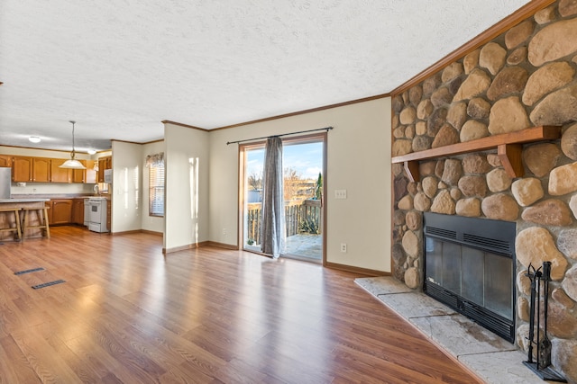 living room featuring ornamental molding, a textured ceiling, a fireplace, and light hardwood / wood-style flooring