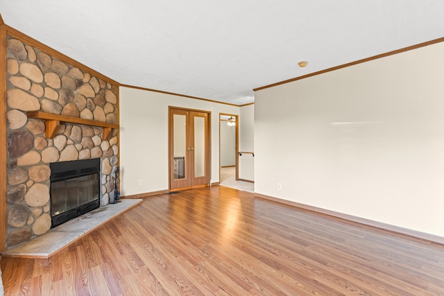 unfurnished living room featuring crown molding, light wood-type flooring, a fireplace, and french doors