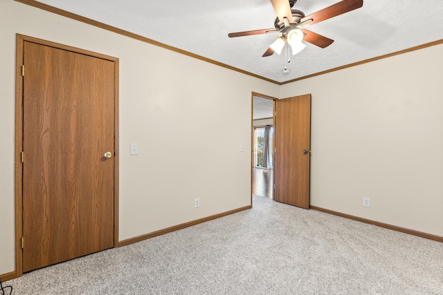 unfurnished room with a textured ceiling, ornamental molding, light colored carpet, and ceiling fan