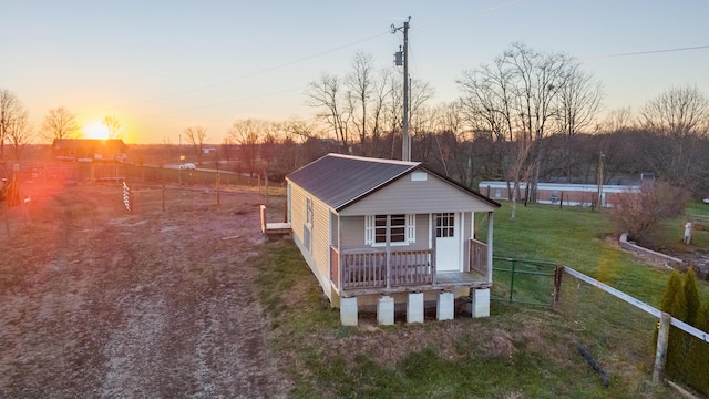 back house at dusk with a yard and a porch