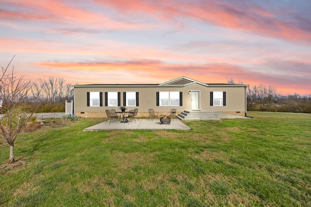 back house at dusk with a lawn and a patio area