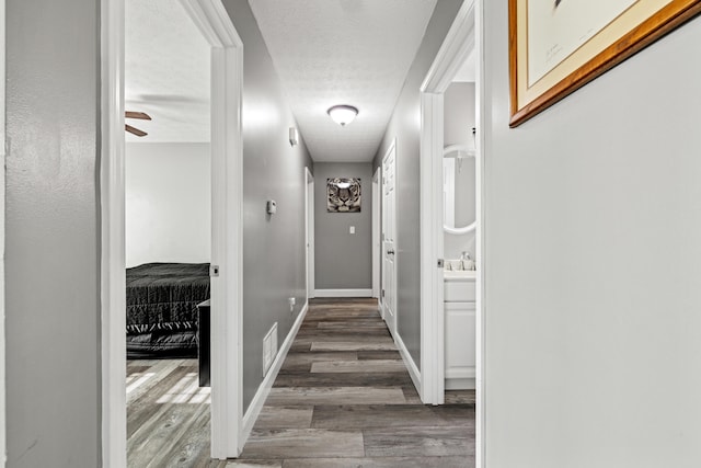 corridor featuring a textured ceiling and dark hardwood / wood-style floors