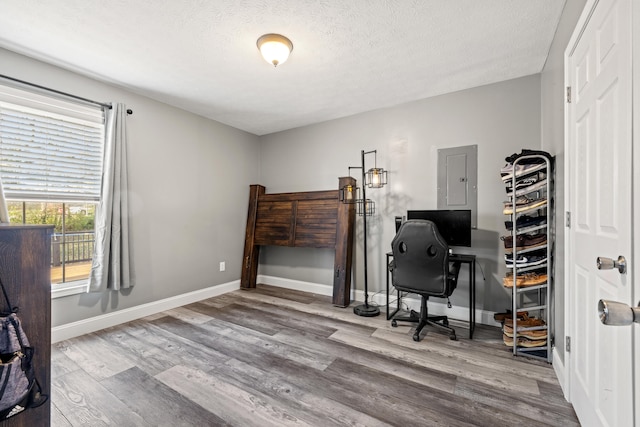 office featuring hardwood / wood-style floors, a textured ceiling, and electric panel