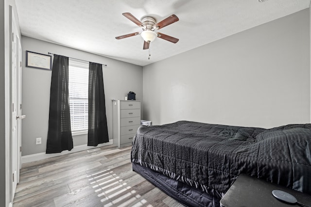 bedroom featuring ceiling fan, a textured ceiling, and light wood-type flooring