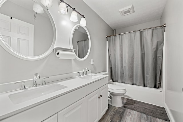 full bathroom featuring hardwood / wood-style floors, vanity, toilet, a textured ceiling, and shower / tub combo