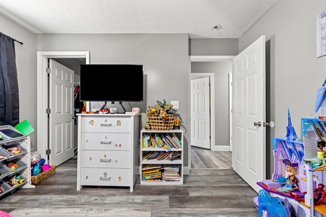 game room with a textured ceiling and dark wood-type flooring