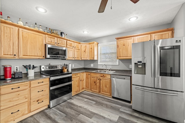 kitchen with sink, light wood-type flooring, a textured ceiling, and appliances with stainless steel finishes