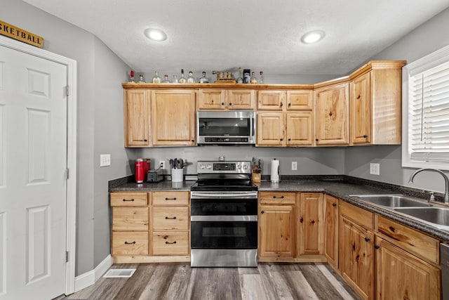 kitchen featuring a textured ceiling, wood-type flooring, sink, and appliances with stainless steel finishes