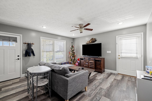 living room with hardwood / wood-style flooring, ceiling fan, and a textured ceiling