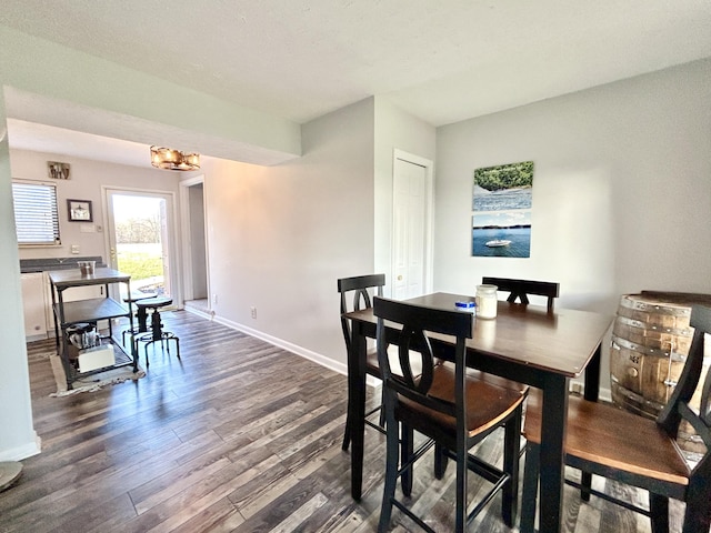 dining room with dark wood-type flooring and an inviting chandelier