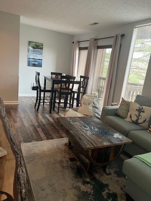 living room with a textured ceiling and dark wood-type flooring