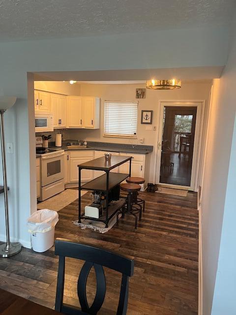 kitchen with hardwood / wood-style flooring, white range with electric stovetop, white cabinets, and a textured ceiling