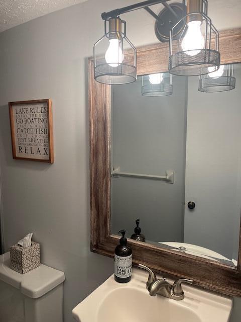 bathroom featuring a textured ceiling, toilet, and sink