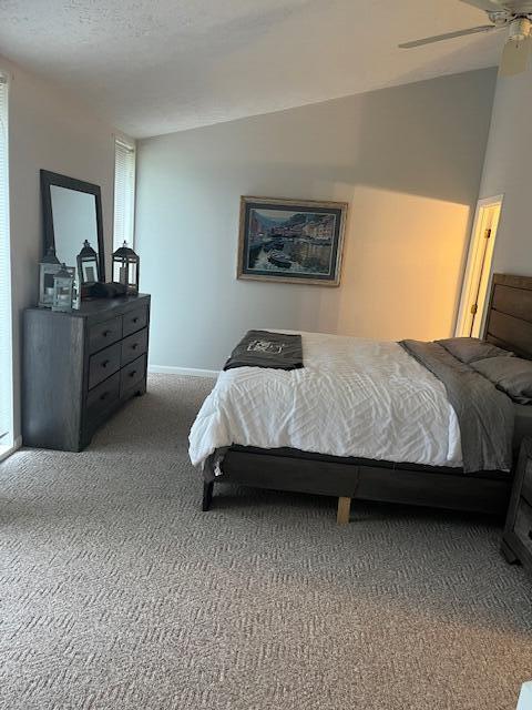 carpeted bedroom with a textured ceiling, ceiling fan, and vaulted ceiling