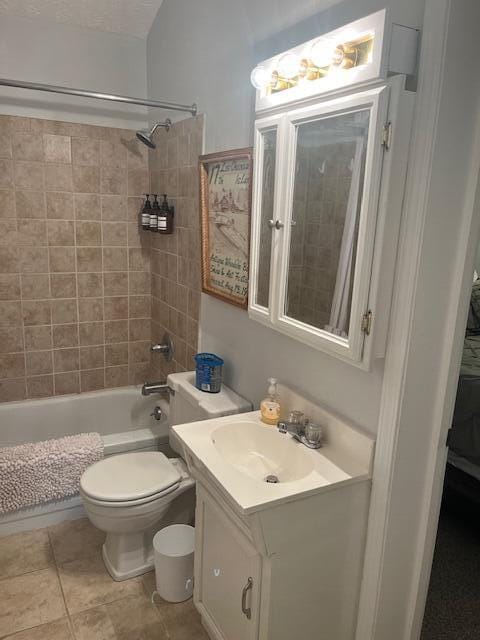 full bathroom featuring tile patterned flooring, vanity, tiled shower / bath combo, and toilet