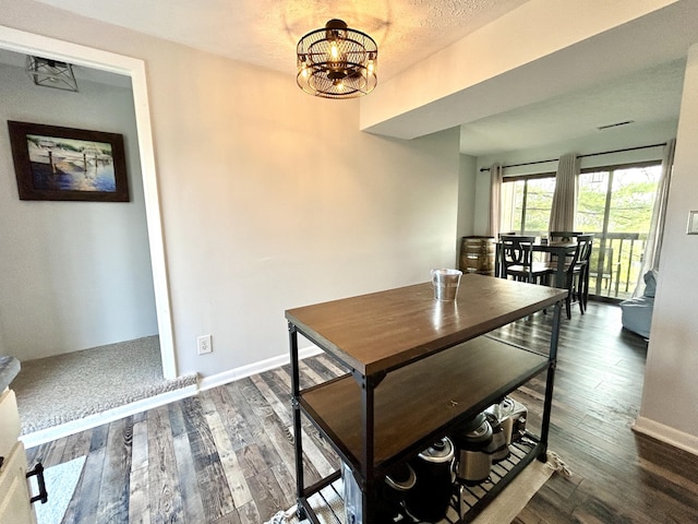 dining space with a textured ceiling, a notable chandelier, and dark wood-type flooring