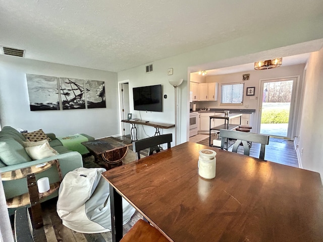 dining area featuring wood-type flooring and a textured ceiling