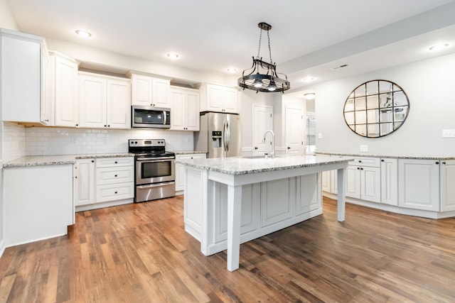 kitchen with a center island with sink, white cabinets, wood-type flooring, and appliances with stainless steel finishes